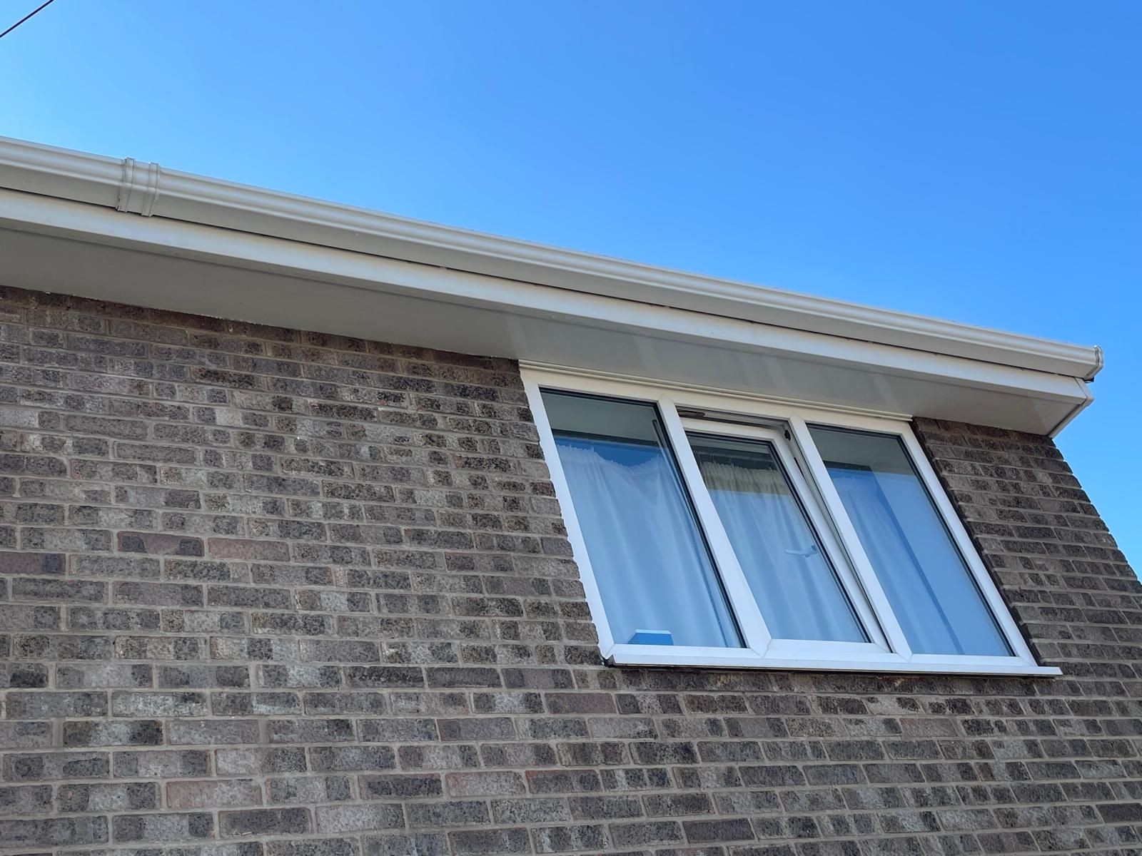 Professionally cleaned white fascia's, soffits, and gutters on a brick property.