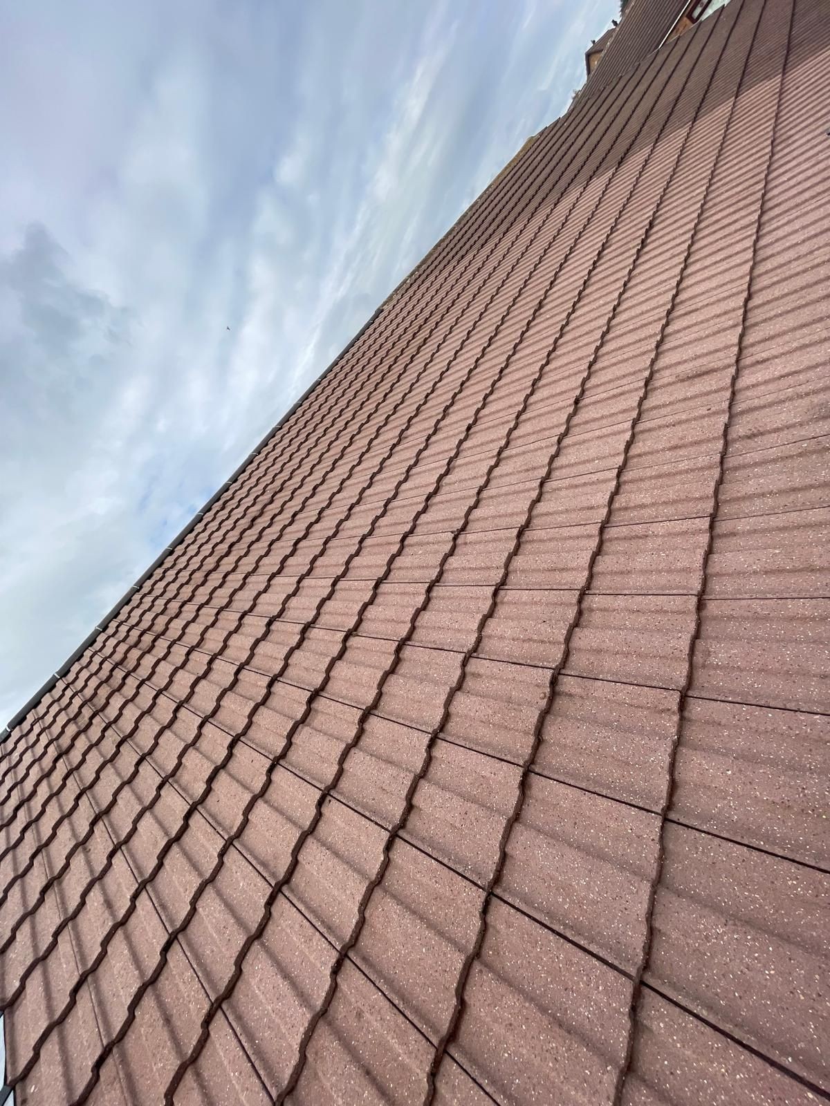 Clean red concrete roof tiles, free from moss, algae, or lichen, treated with biocide for long-lasting protection