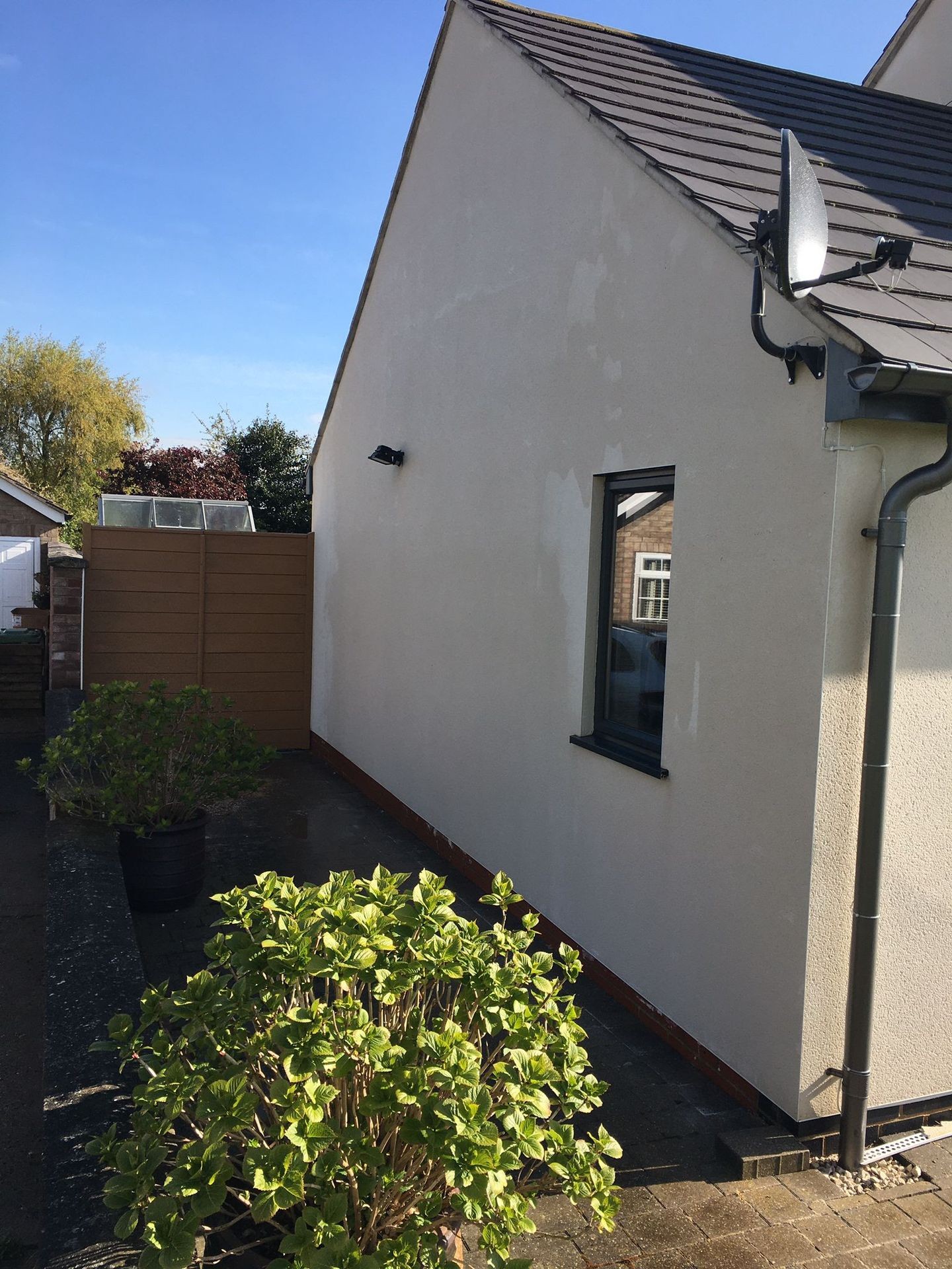 Side of a house with clean render after soft washing service, showing restored appearance and spotless surface.