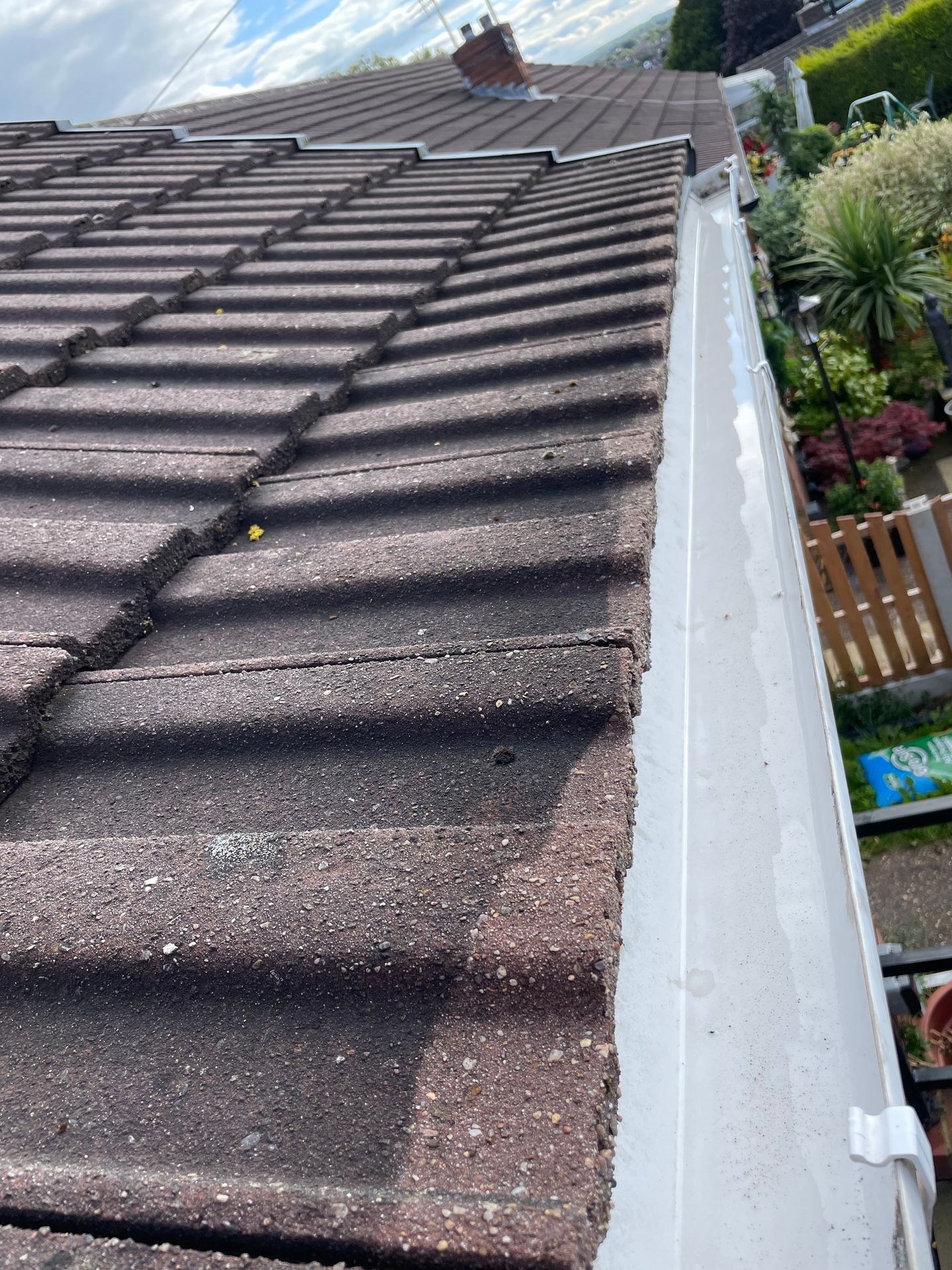 Clean and clear white gutters running along the edge of a bungalow roof.