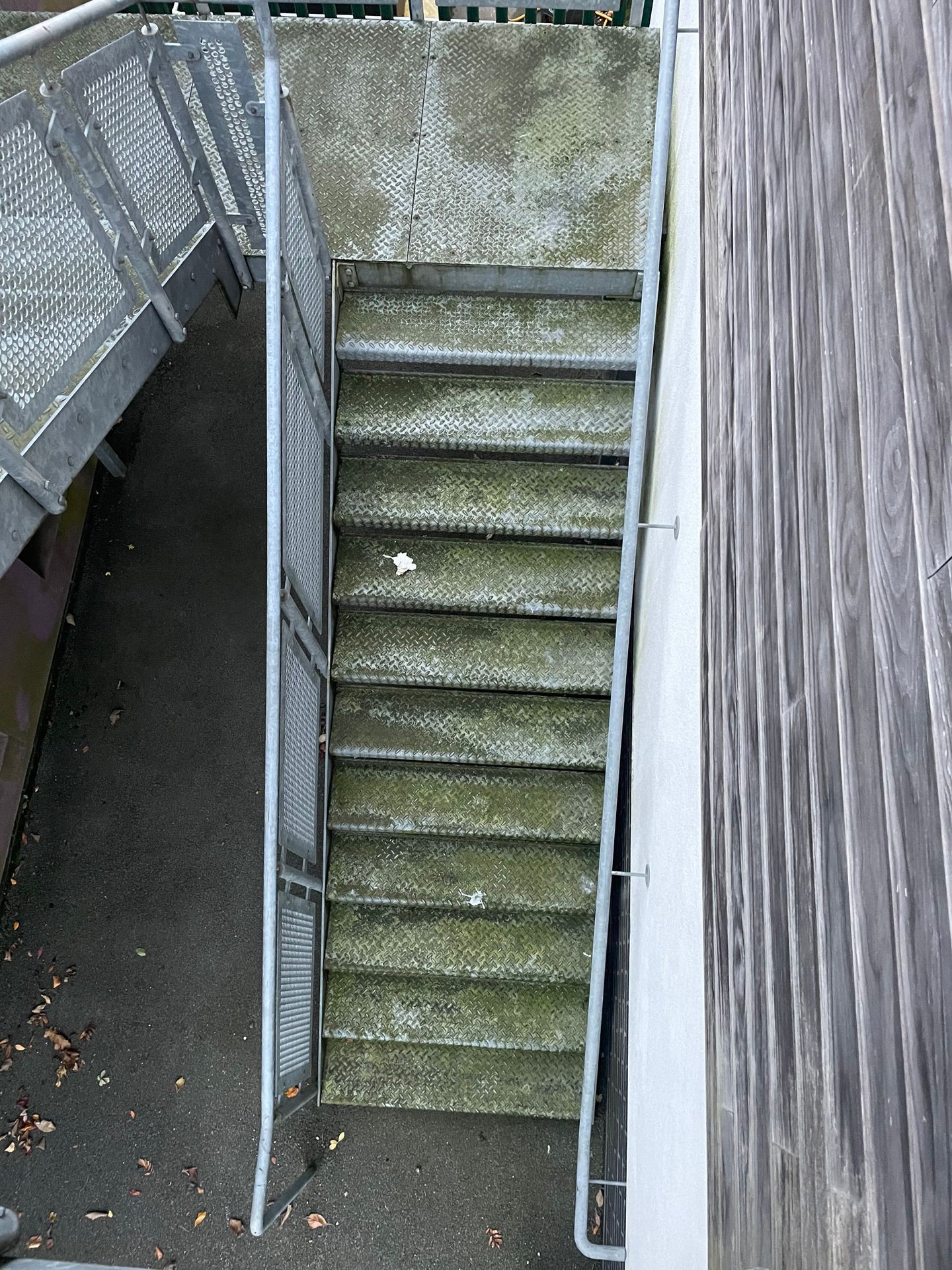 A set of stainless steel fire escape steps covered in dirt and grime, showing signs of weathering and in need of professional cleaning to restore their original shine.