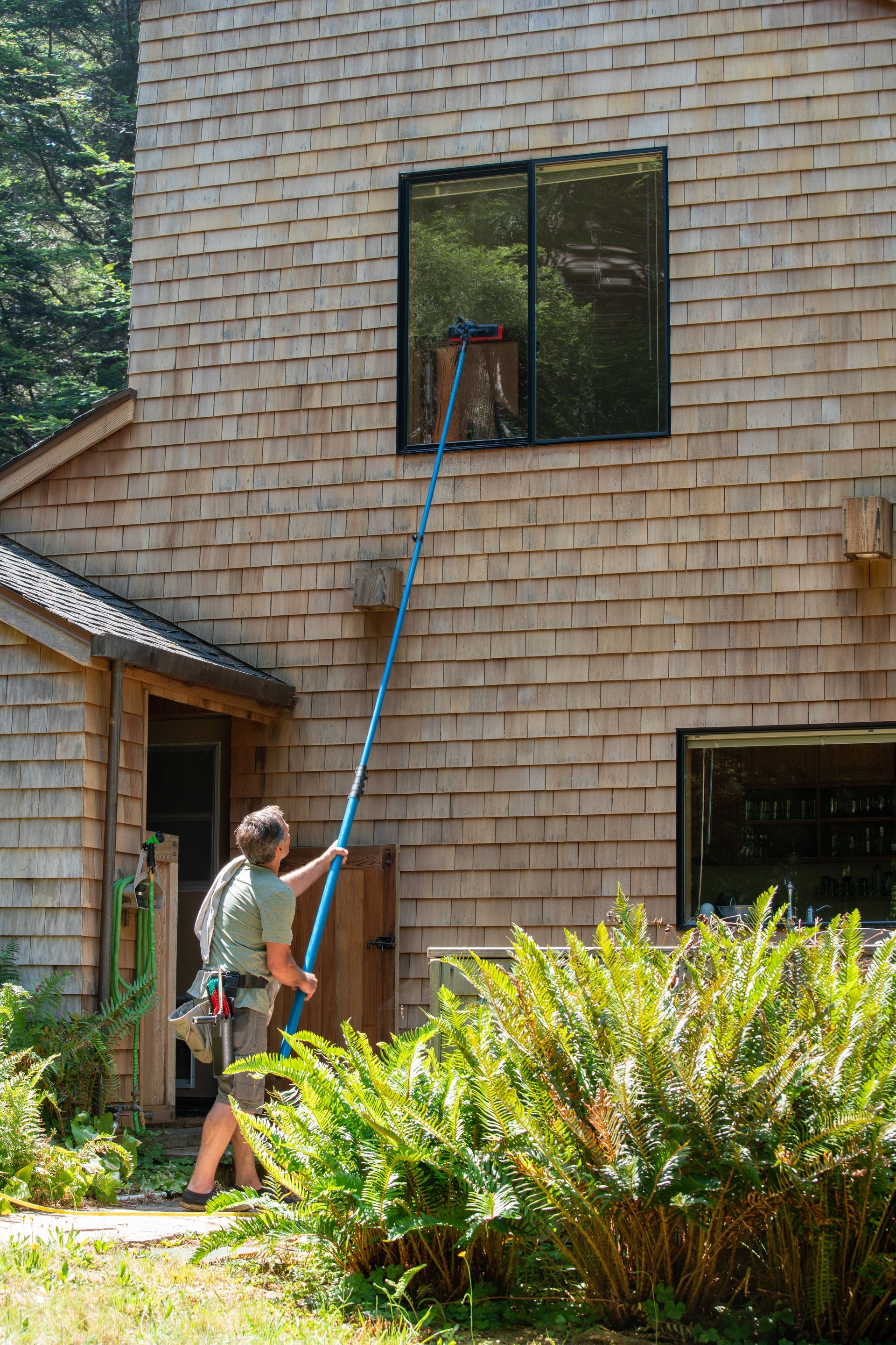 Man washing window with long pole and brush